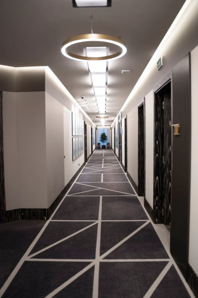 Hotel corridor with circular pendant light and linear recessed ceiling lighting — Hypro ceiling and renovation
