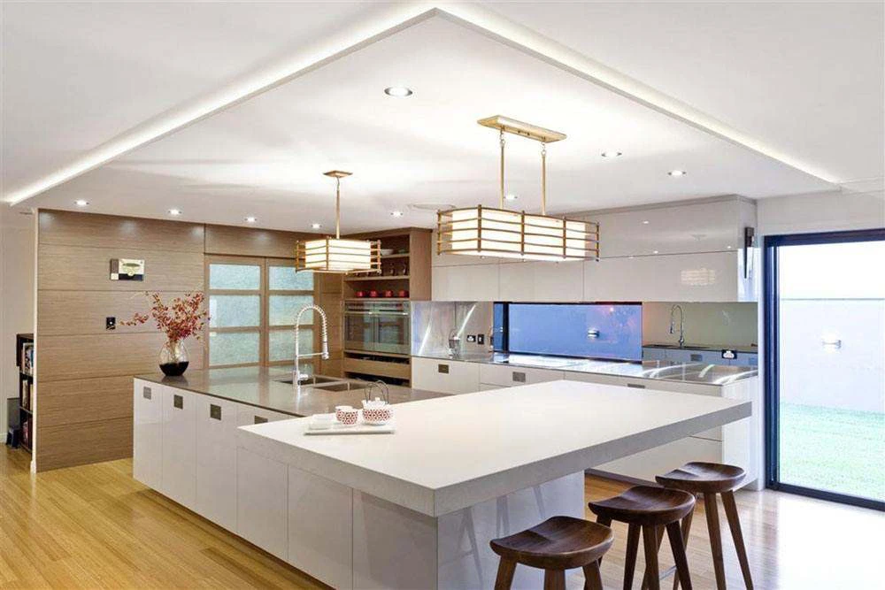 Modern kitchen with a recessed plaster ceiling, cove lighting and pendant lights by Hypro Renovation