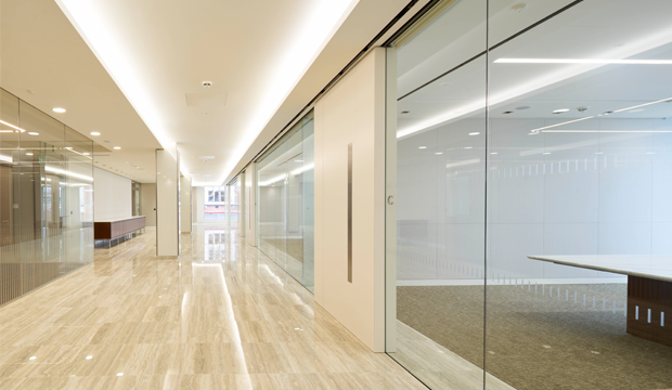 Office corridor with frameless glass partitions and a cove-lit plaster ceiling — Hypro ceiling and partition work